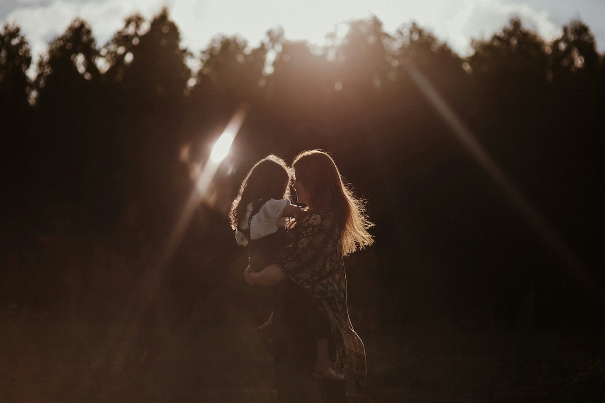 Mother and daughter holding each other in an open field