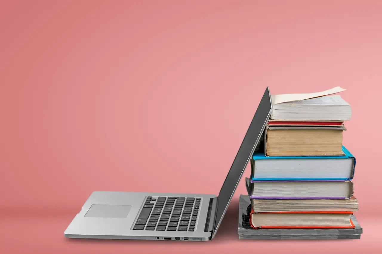 Laptop leaning againt books - How To Summarize An Article With AI