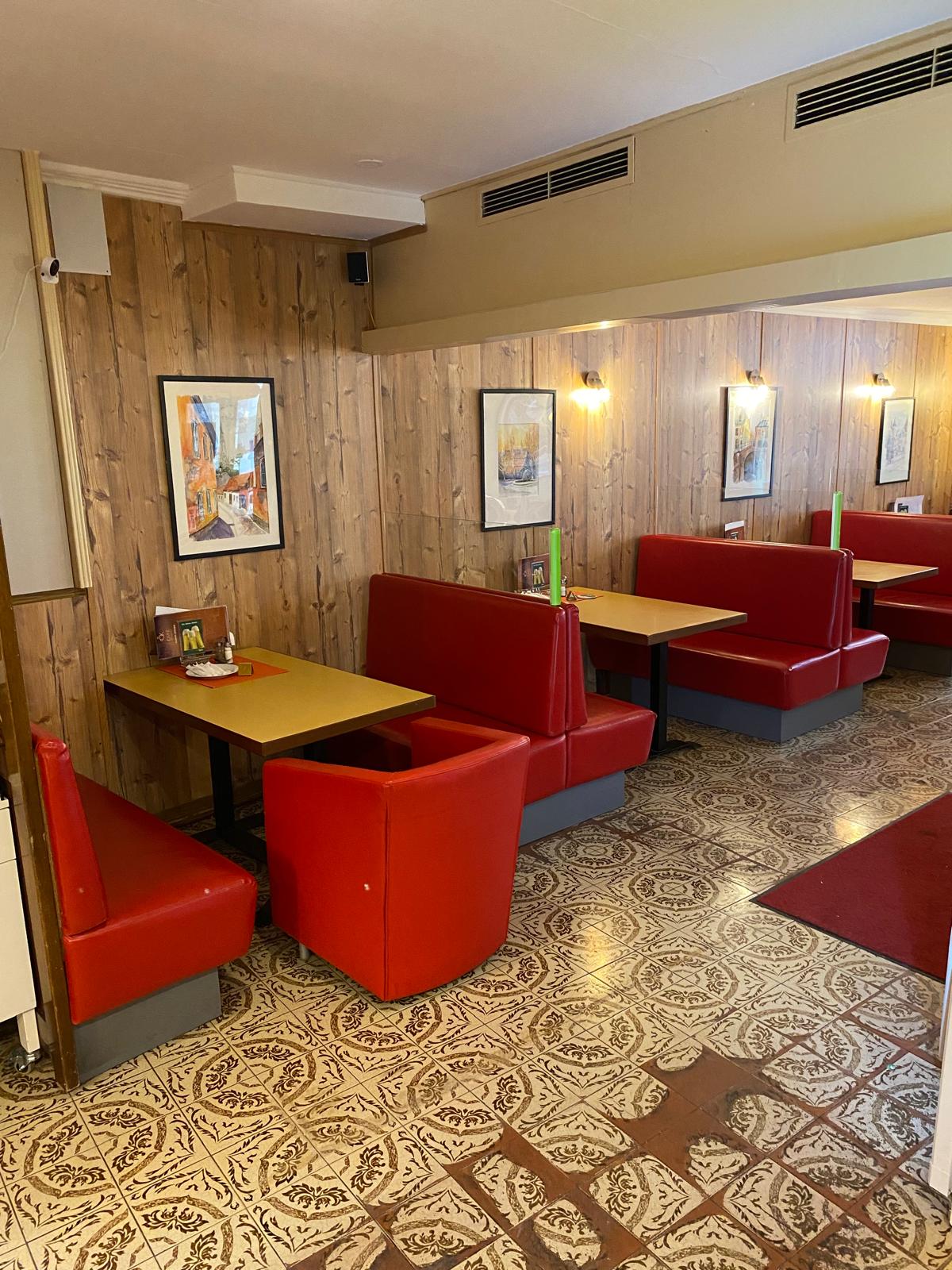 Wooden outdoor table set with multiple plates of food, including dips, salads, potatoes with cheese, and glasses of water, with hands reaching in to eat.