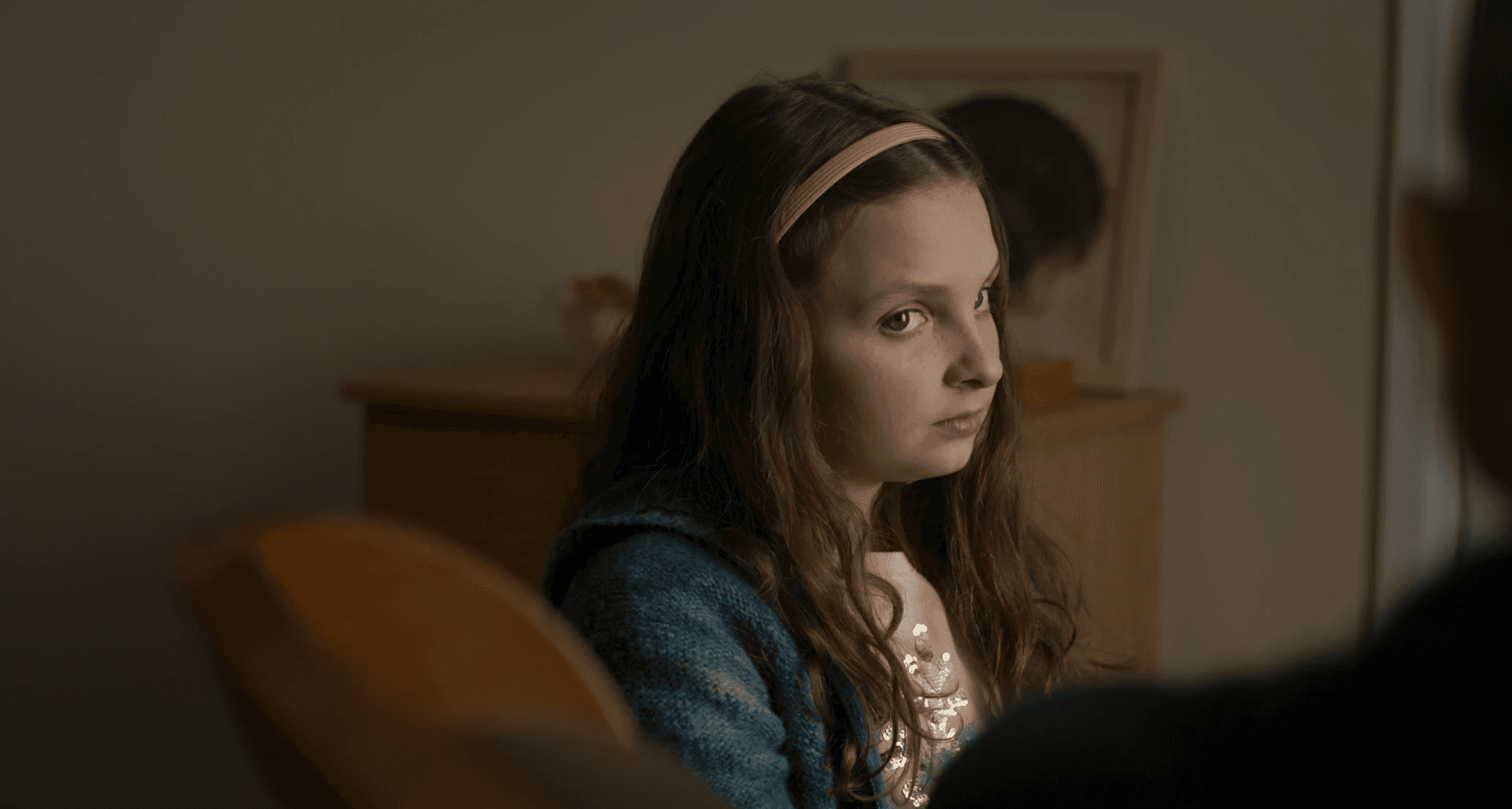 Une petite fille regarde l'homme assit en face d'elle d'un air grave.