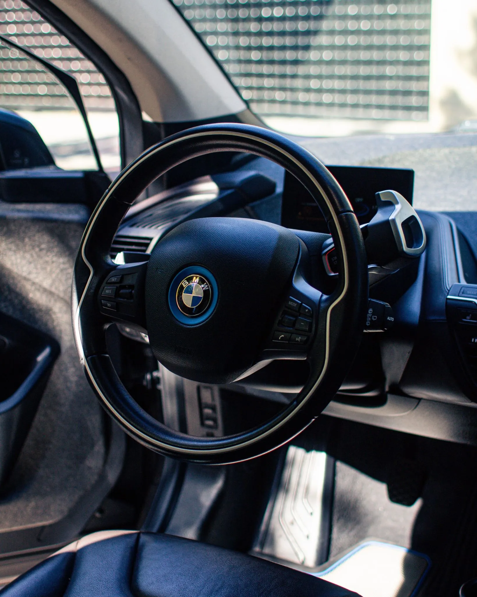 Volante BMW i3 con pantalla central y tablero digital visibles desde la puerta del conductor