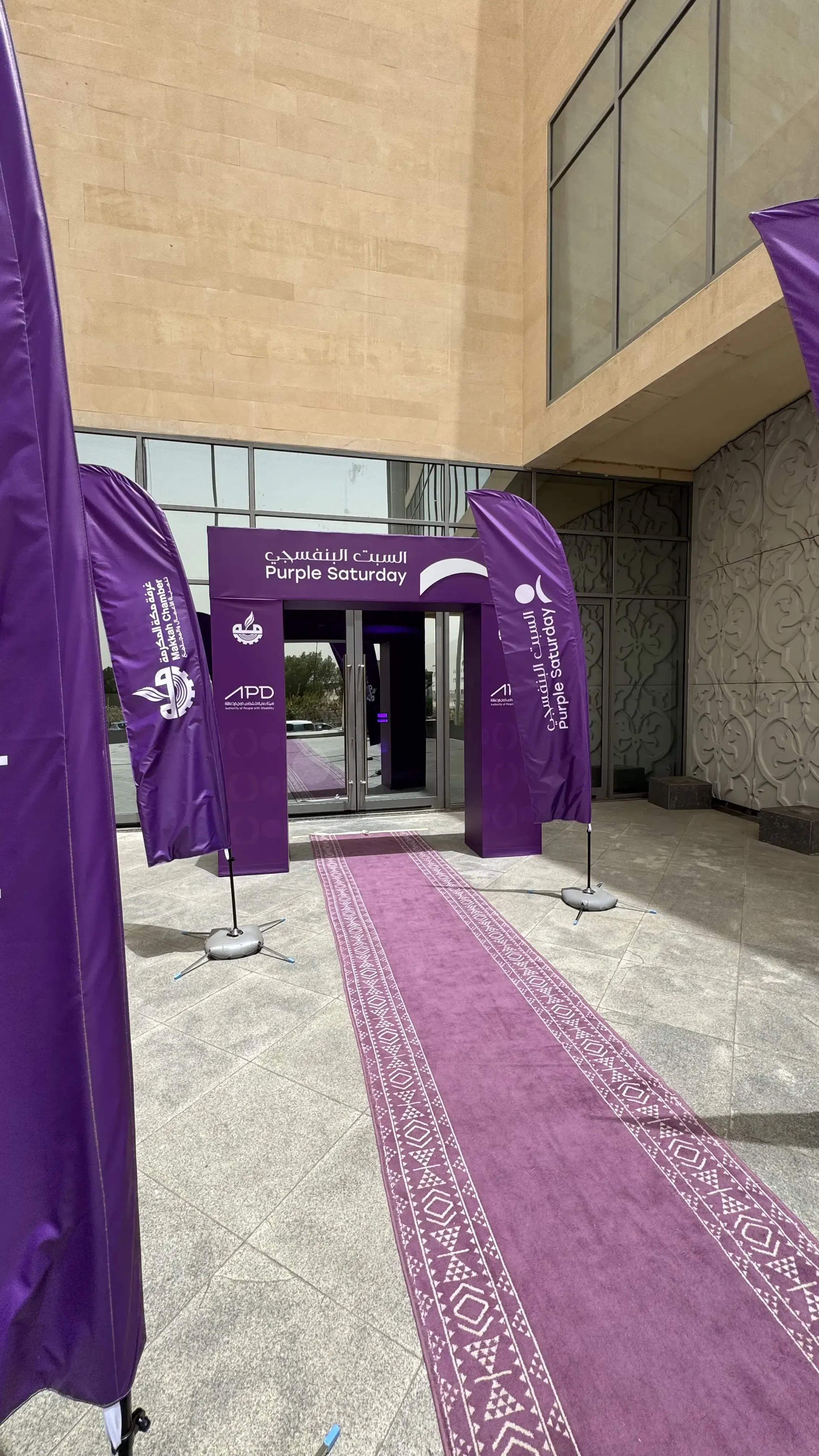 Purple Saturday exterior event entrance with multiple branded flags and doorway signage