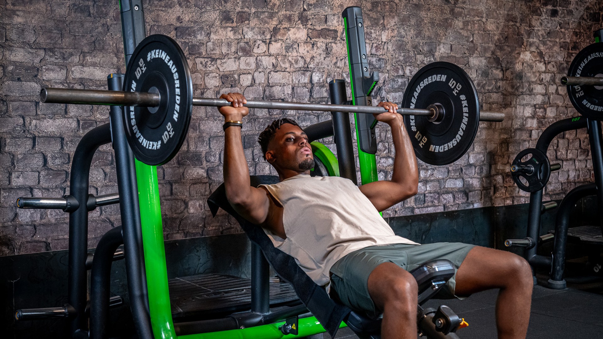 Athletischer Mann trainiert konzentriert an einer Schrägbank mit Langhantel im modernen Fitnessstudio, sichtbare Muskelspannung und natürliche Körperhaltung, Symbol für Intervallfasten und Krafttraining im Alltag