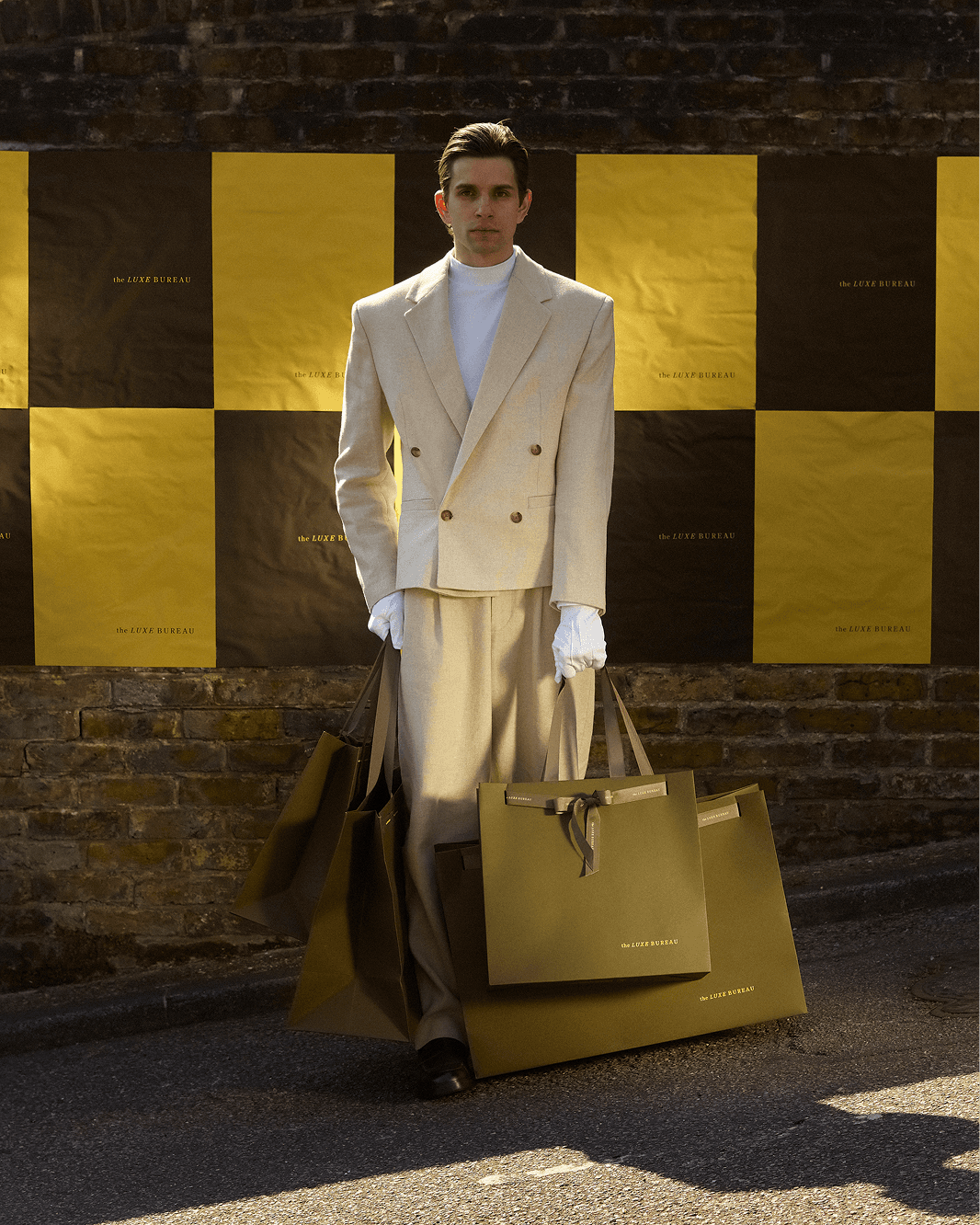 the luxe bureau model delivering gifts in front of braded posters on the street