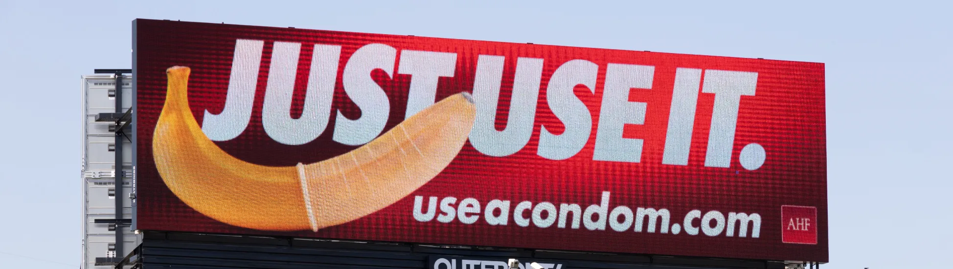 a man walking down a street past a large poster