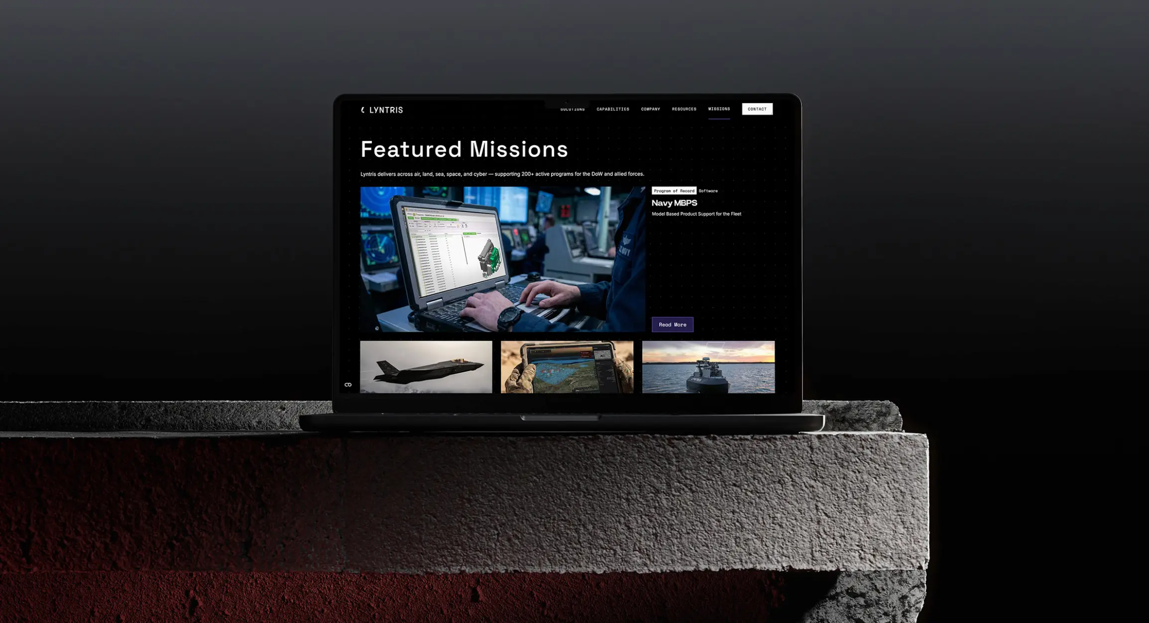 A laptop on a stone surface displays the "LYNTRIS" site with "Featured Missions" and a highlighted "Read More" button, reinforcing defense tech marketing messaging through mission-focused B2B content.
