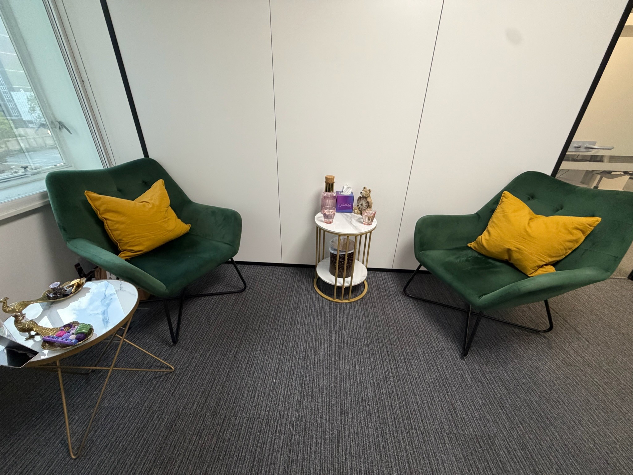 Two green armchairs with yellow cushions in the Core Psychotherapy counselling room