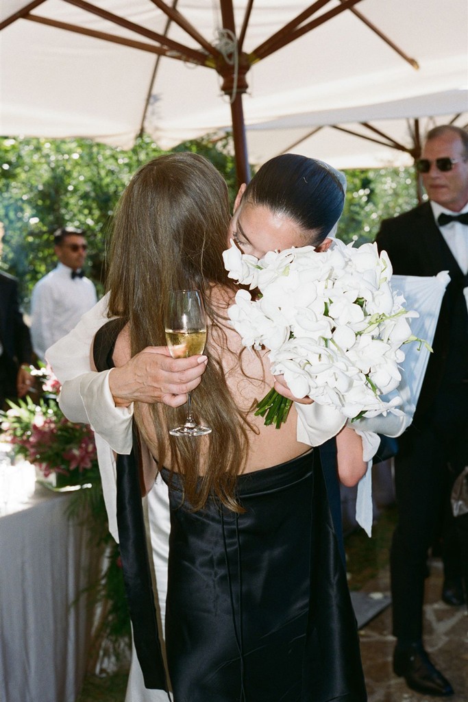 Bride embracing a guest while holding a white bouquet during the reception