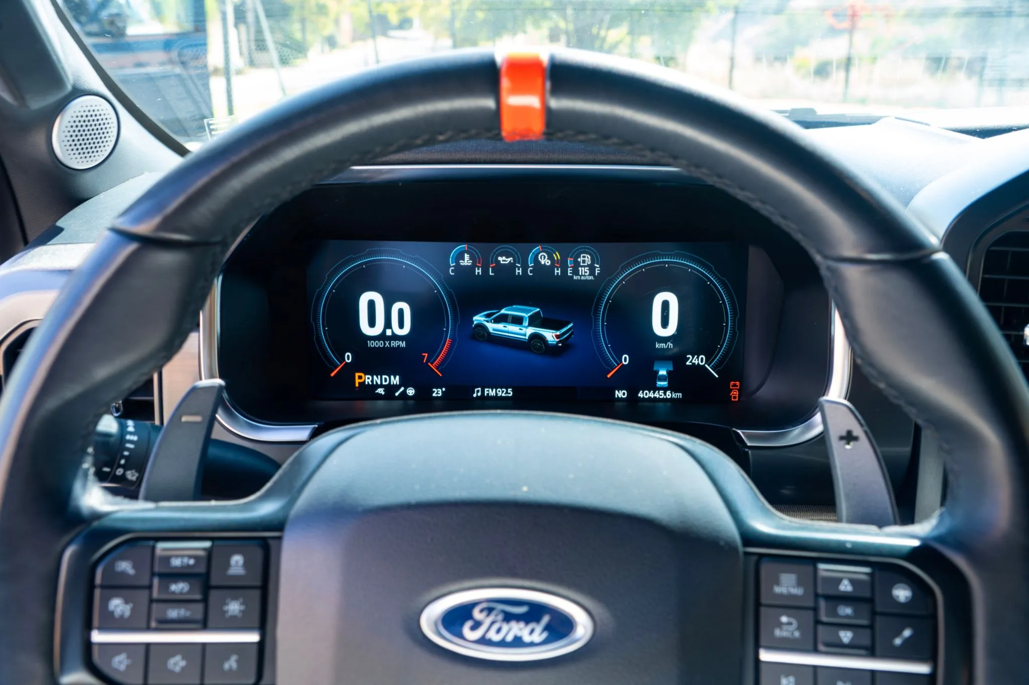 Interior de Ford F-150 Raptor blanca con volante, pantalla central grande y consola ancha