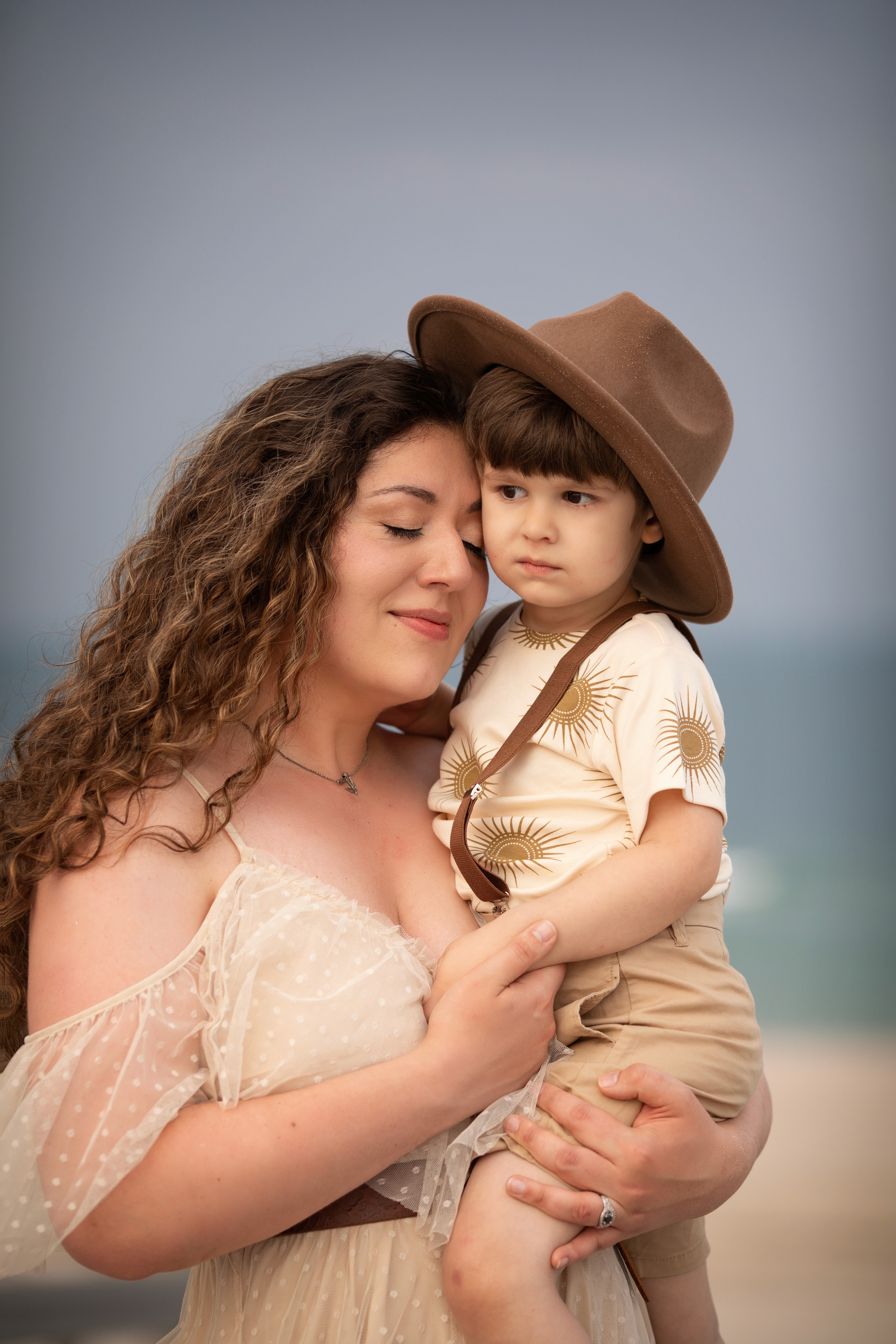 Mother holding her young child during a warm sunset family session at the beach.
