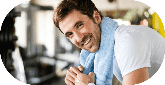 A man smiling at the camera after just finishing his workout routine