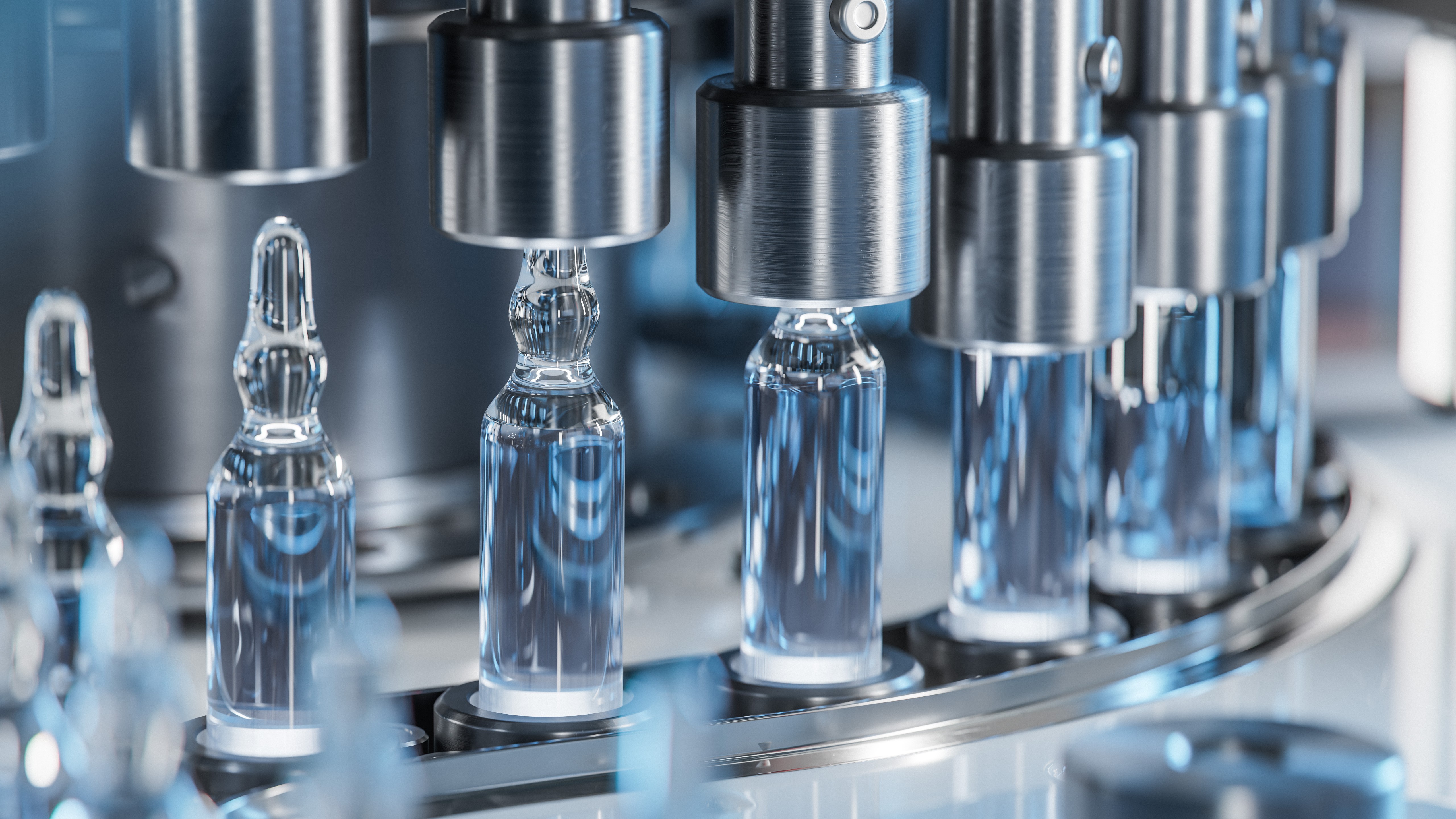 Close-up of clear glass pharmaceutical ampoules being filled on a stainless steel production line