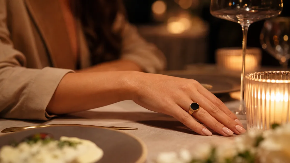Woman's hand at a candlelit dinner table wearing a discreet dark-screen smart tasbih ring