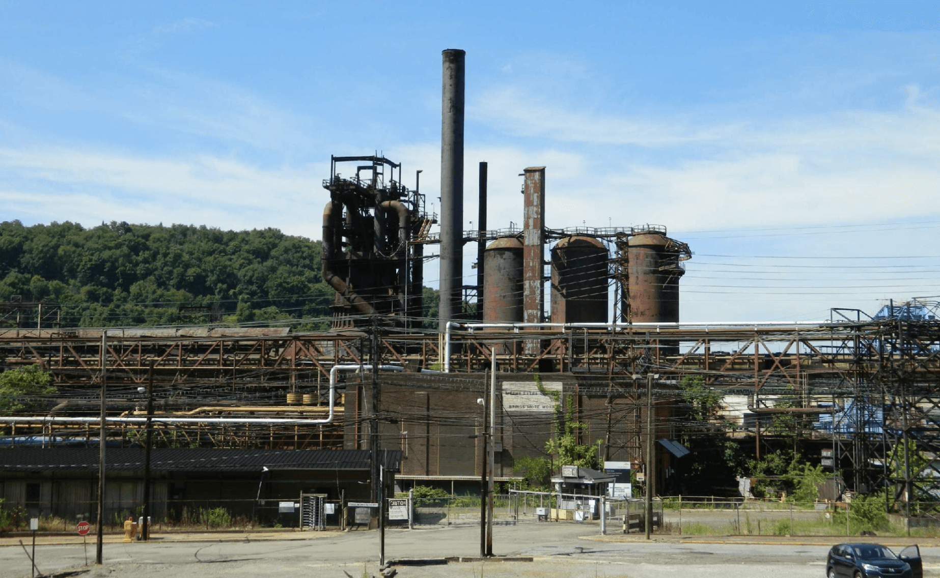 The image depicts a large, industrial, factory with towering smokestacks and a clear sky.
