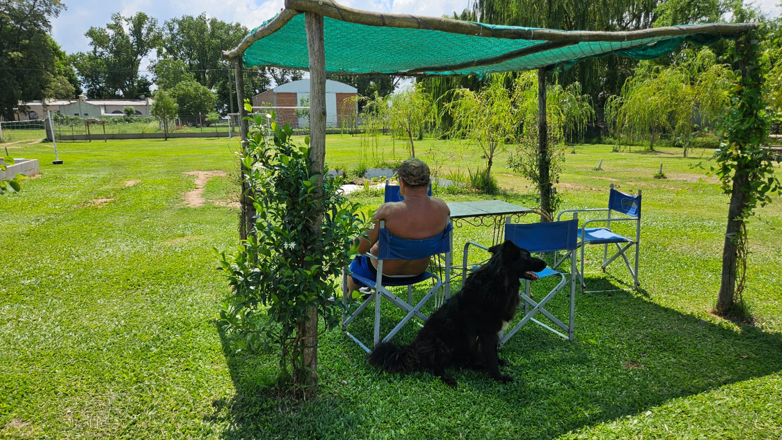 Perro acompañando a su dueño en el jardín exterior de una cabaña pet friendly en Saladillo