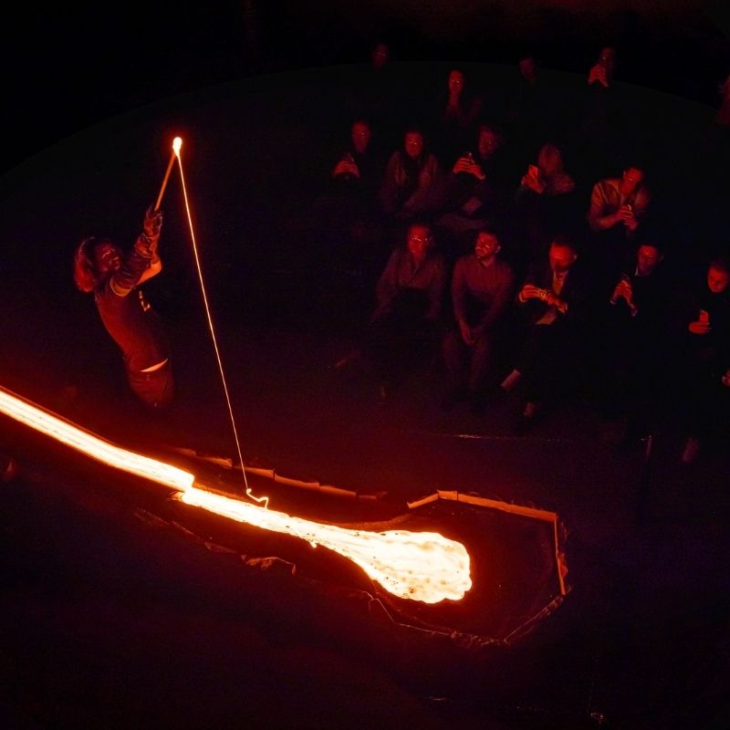 A Lava Master guides visitors through a live demonstration of real molten lava at Lava Show, using a metal rod to showcase the lava's intense heat and fluid movement as guests watch from just metres away.