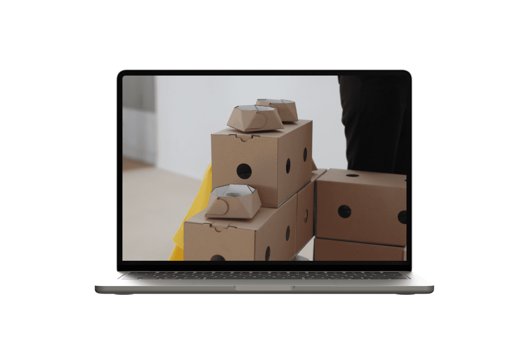 Laptop displaying pixelated modular cardboard packaging elements arranged as blocks.