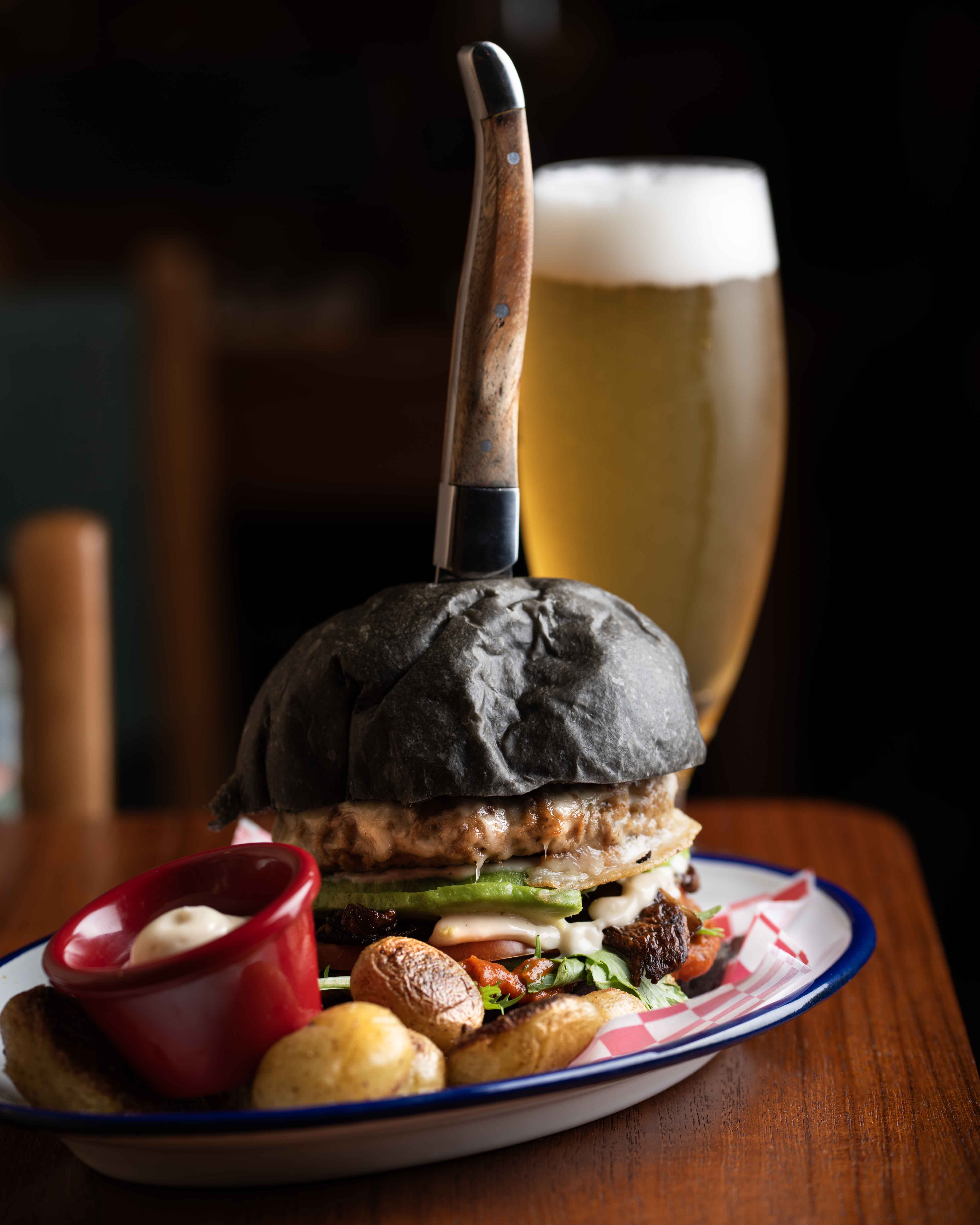 Hamburguesa vegetariana en pan de carbón con cerveza en Faire. Tapas & Wine, Eixample