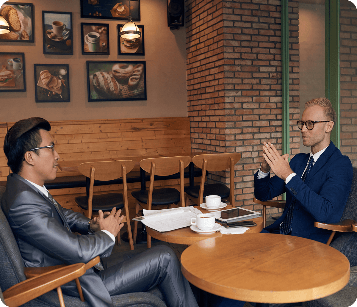 Side view of two businessmen sitting in the cafe discussing piles of documentation