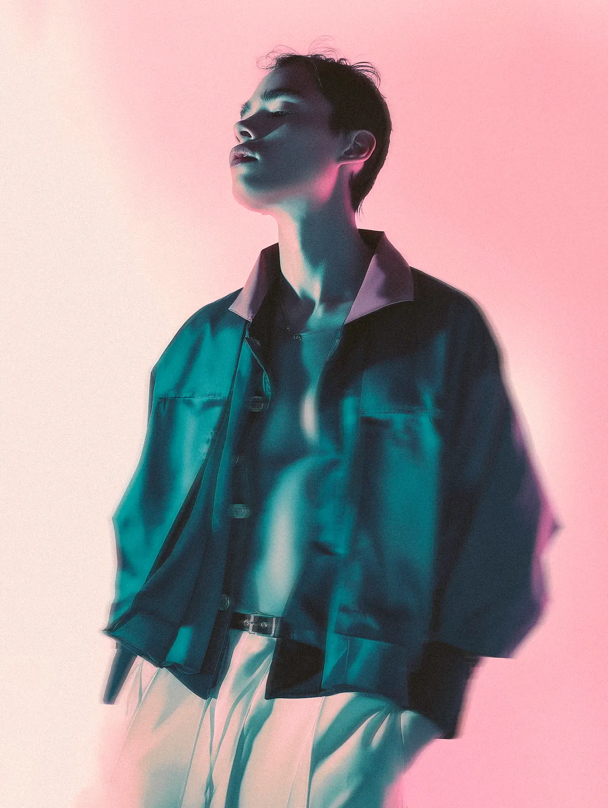 Fashion portrait in an oversized denim jacket against a pale pink background.