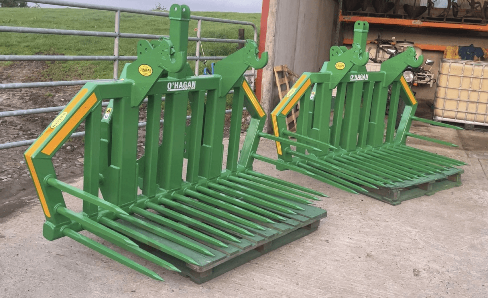 2 Green Stone Forks on pallets in a yard with a farm gate in the background