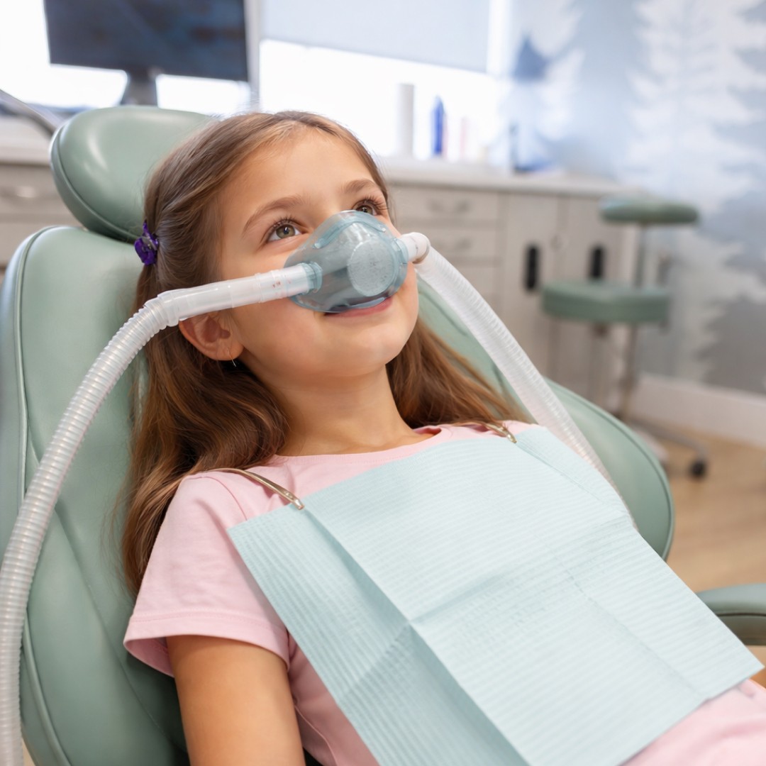 Young girl relaxed and smiling while using a "magic nose" mask for laughing gas during dental treatment.