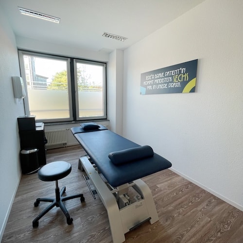 Zu sehen ist unser behandlungsraum 6. Darin steht eine dunkelblaue Behandlungsbank und ein Hocker.