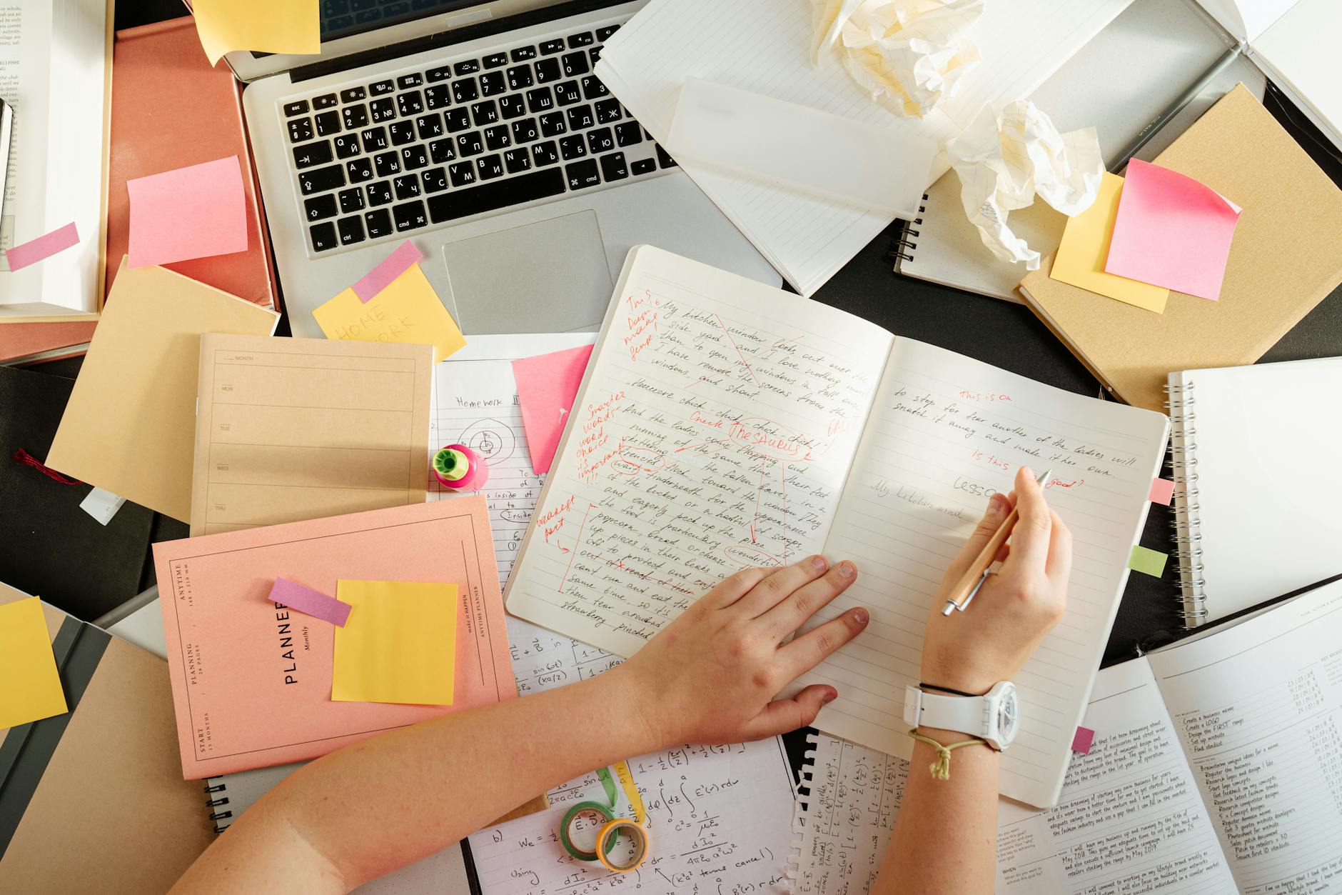 A high school student using a colorful graphic organizer to plan a complex essay at a wooden desk.