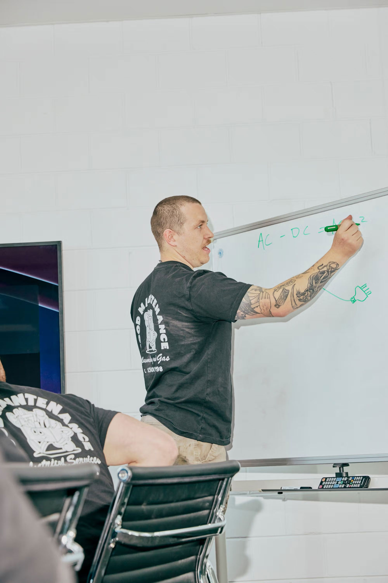 Technician writing AC and DC notes on a whiteboard during team training.