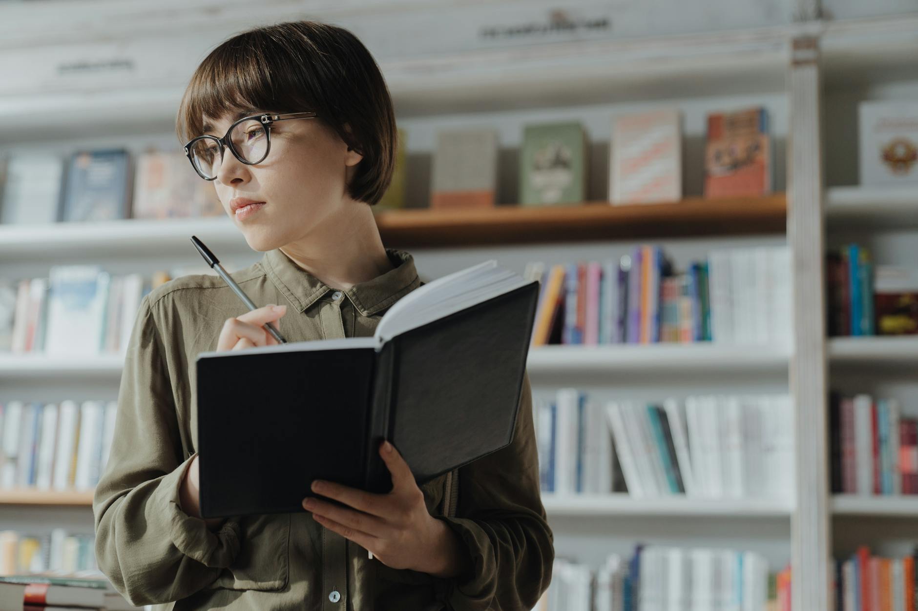 A cluttered desk with a stack of open textbooks and a person holding their head in frustration.