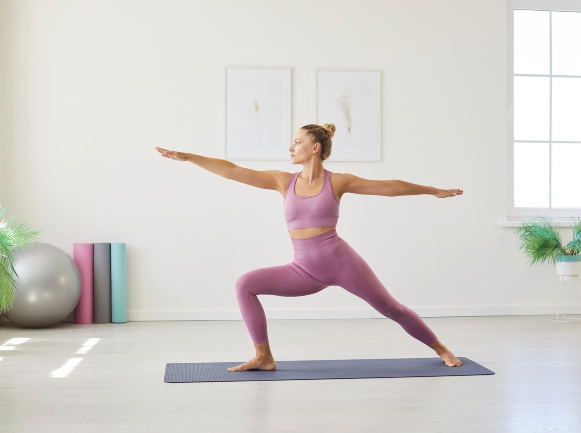 woman doing warrior II as she practices yoga poses to lose weight at home in her studio