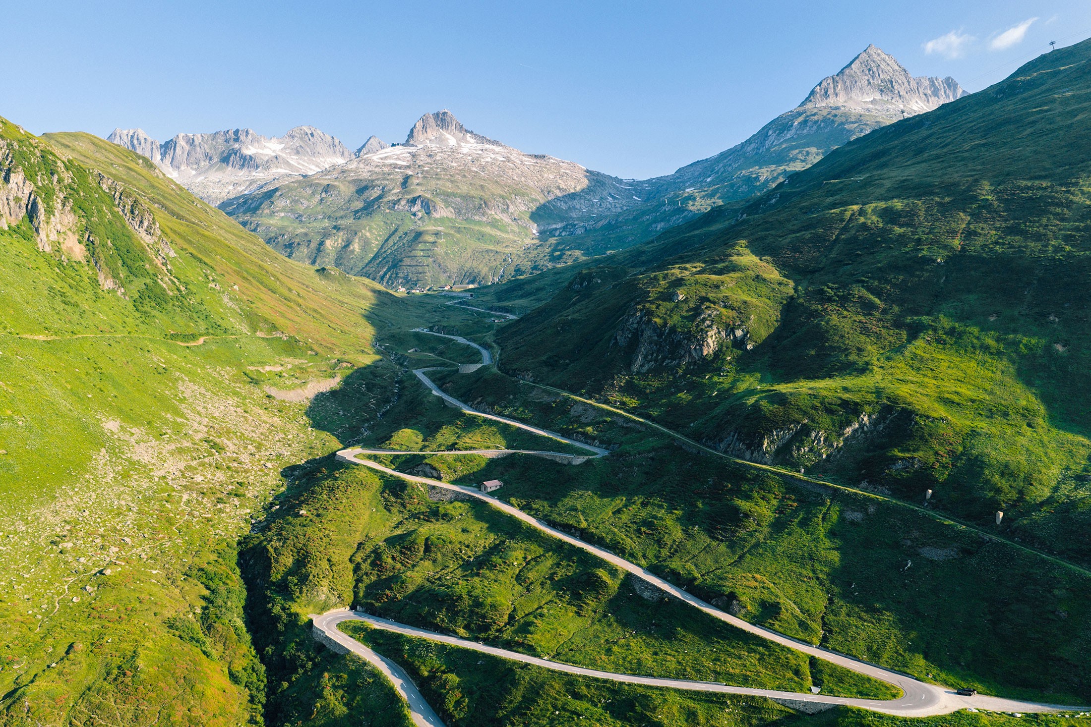 Two cyclists riding up a quiet mountain road in the Swiss Alps