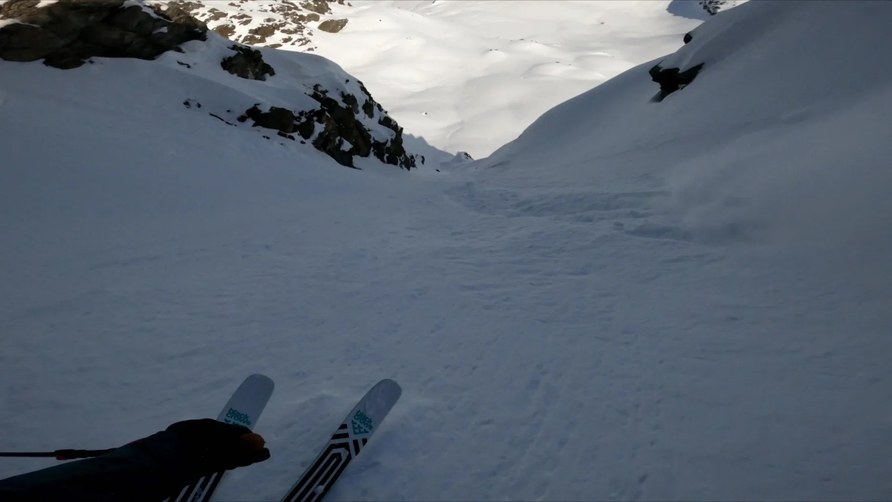Point-of-view shot from the top of a steep couloir with ski tips over the edge