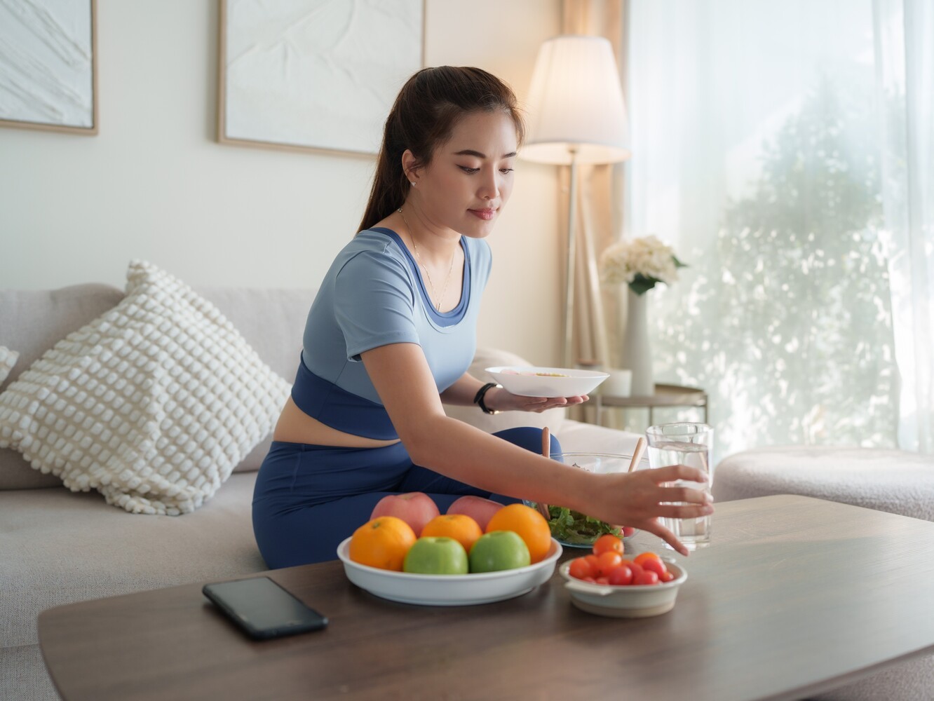 woman gathering healthy snacks and fruit as she prepares for a rest day as part of her running schedule to lose weight