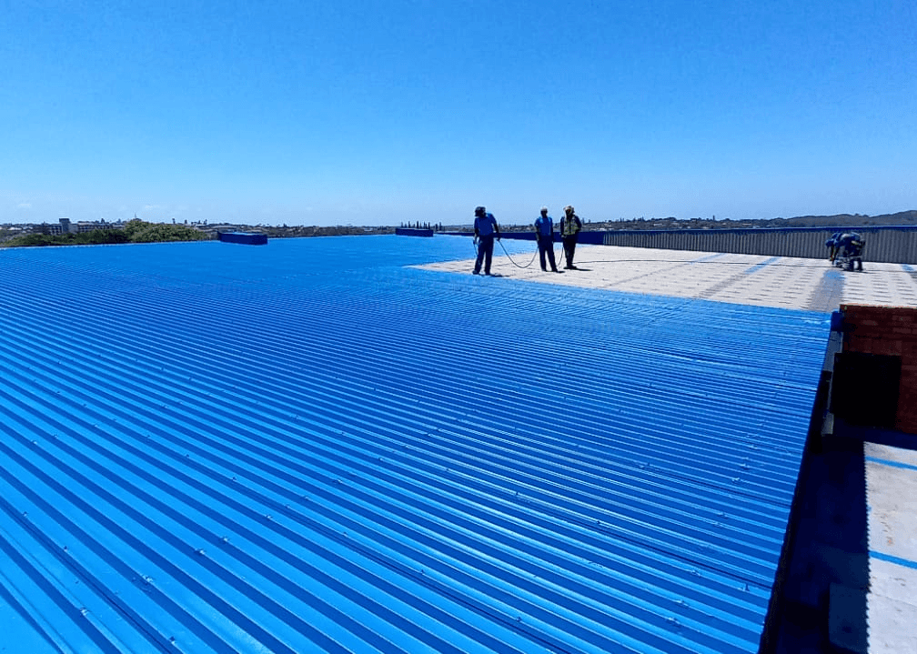 Men spraying a roof with a primer coat