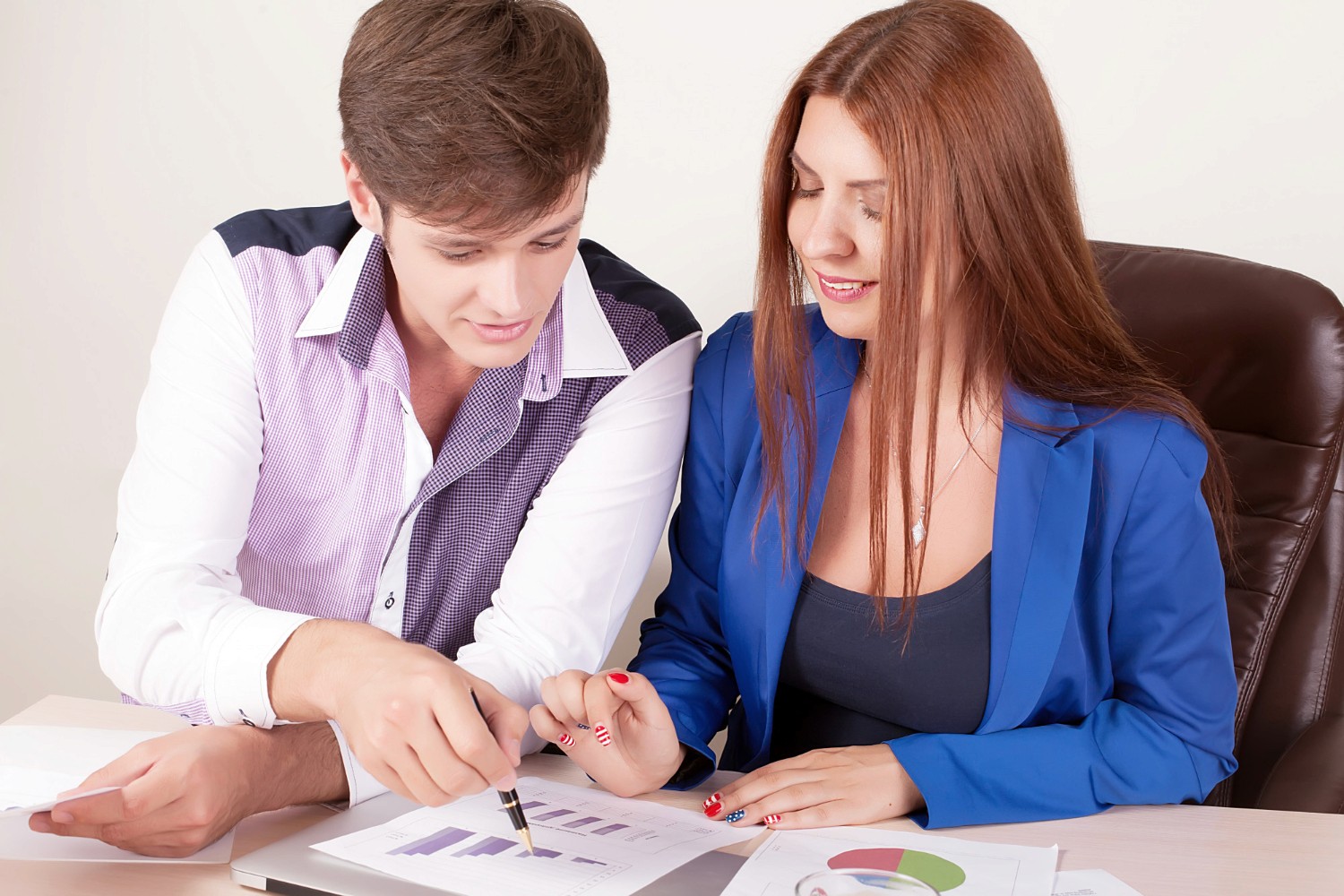  A man and woman are seated together, intently focused on a laptop screen in a collaborative setting.