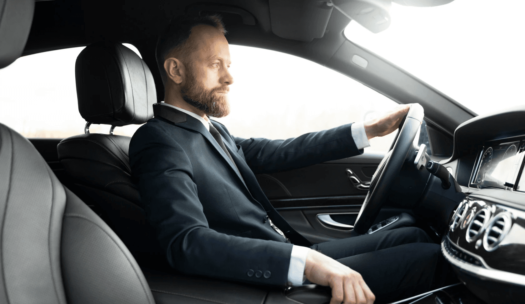 Luxury chauffeur driving a premium vehicle, showcasing professional service and comfort for airport transfers.