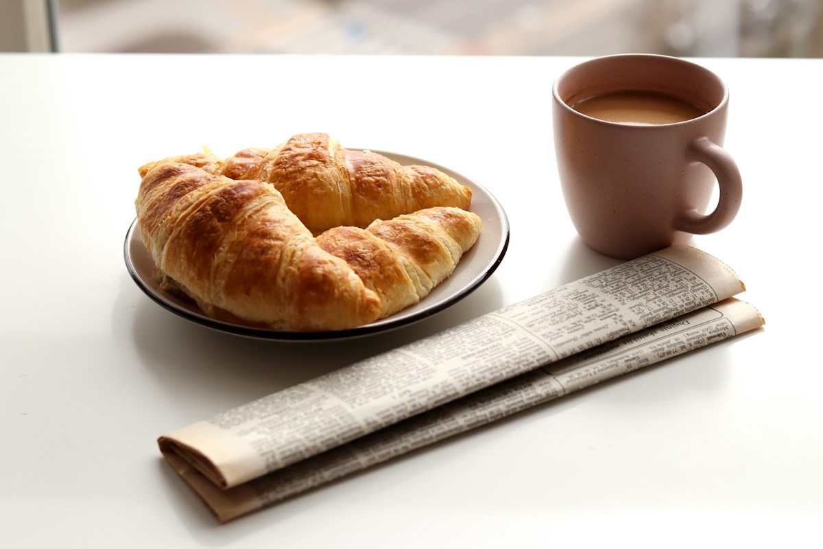 A plate of croissants next to a cup of coffee