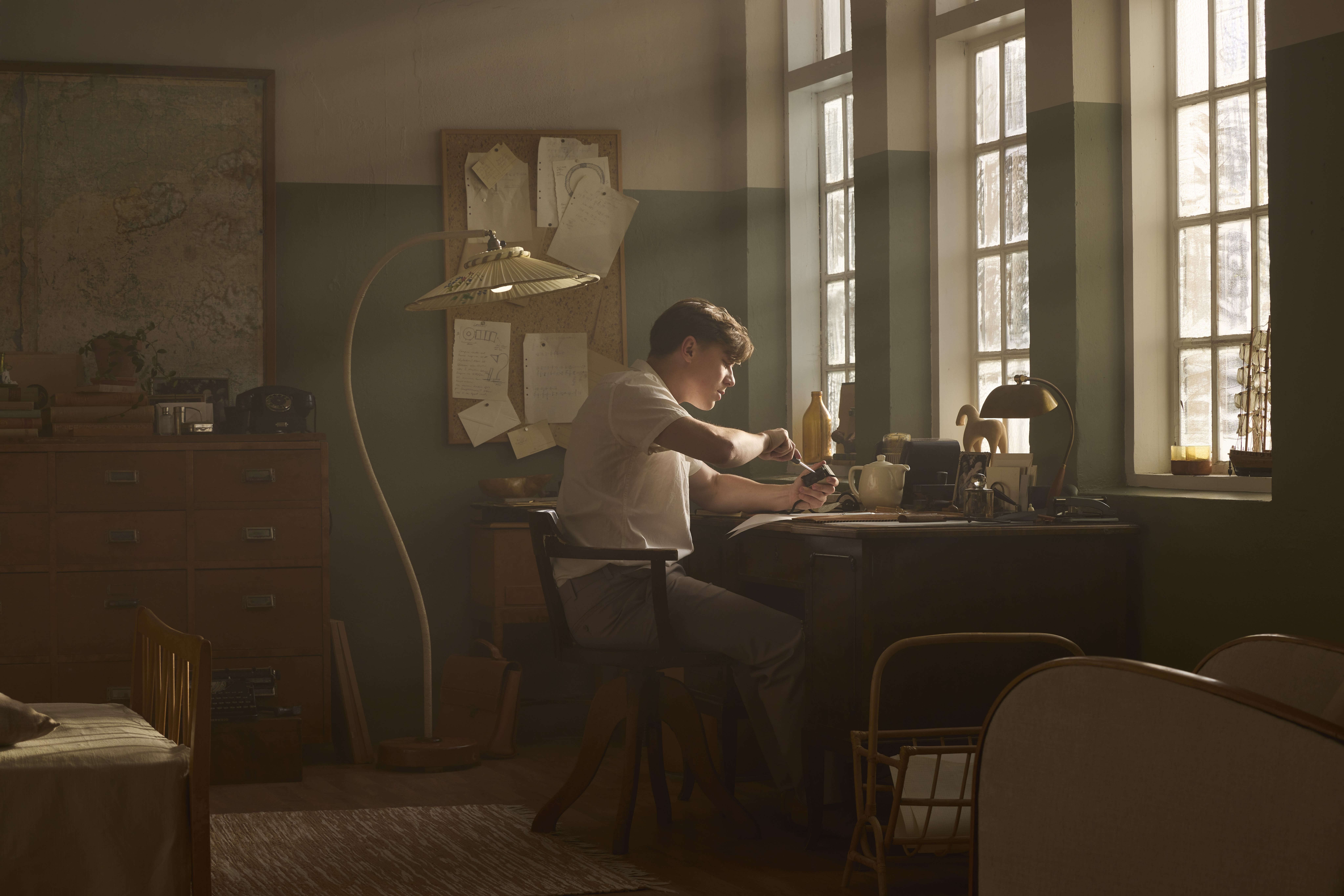 Modern glass and steel building with warm wooden ceilings, surrounded by lush greenery, blending contemporary architecture with nature.