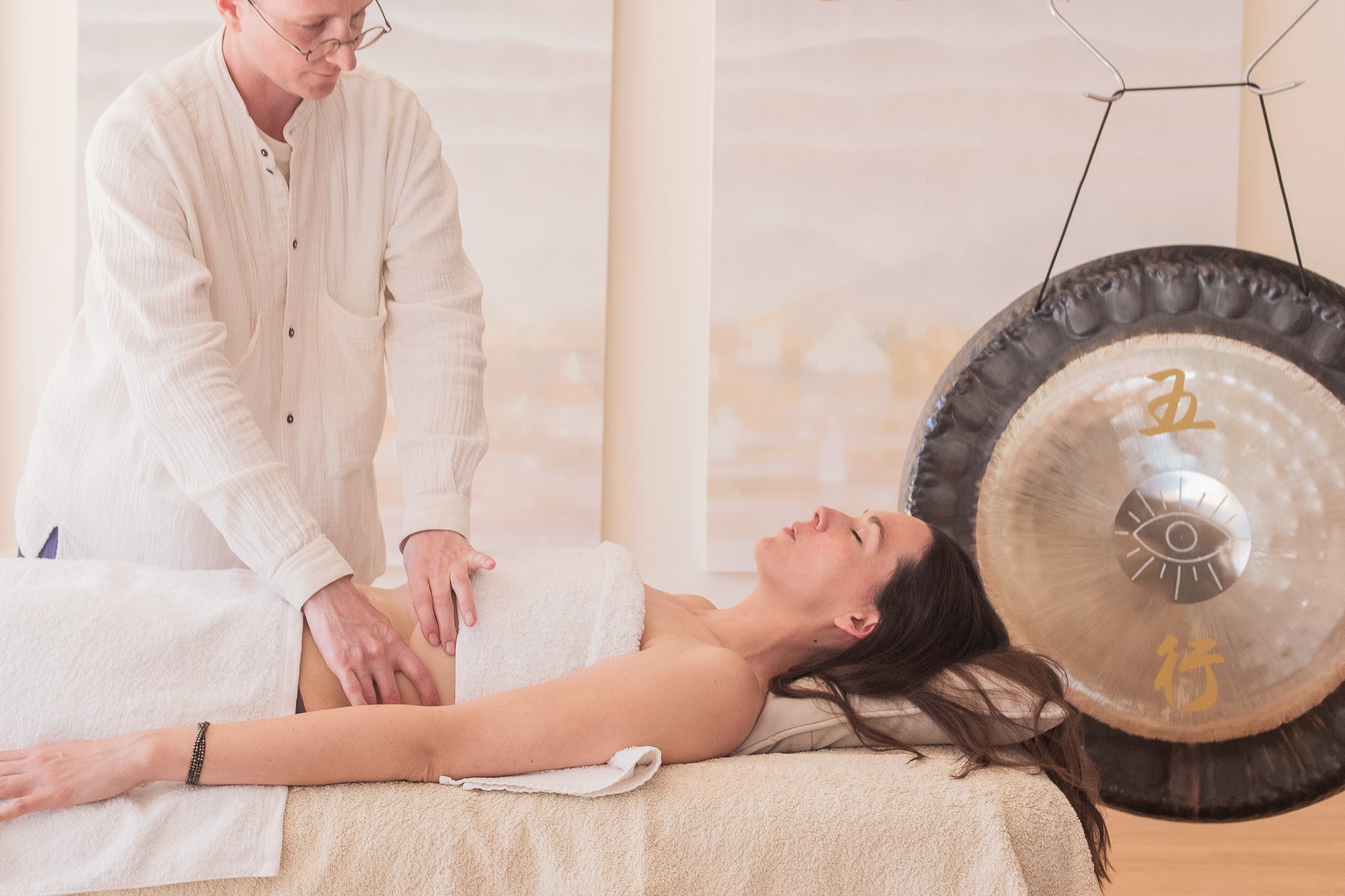 a woman laying on a bed with hot stones on her back