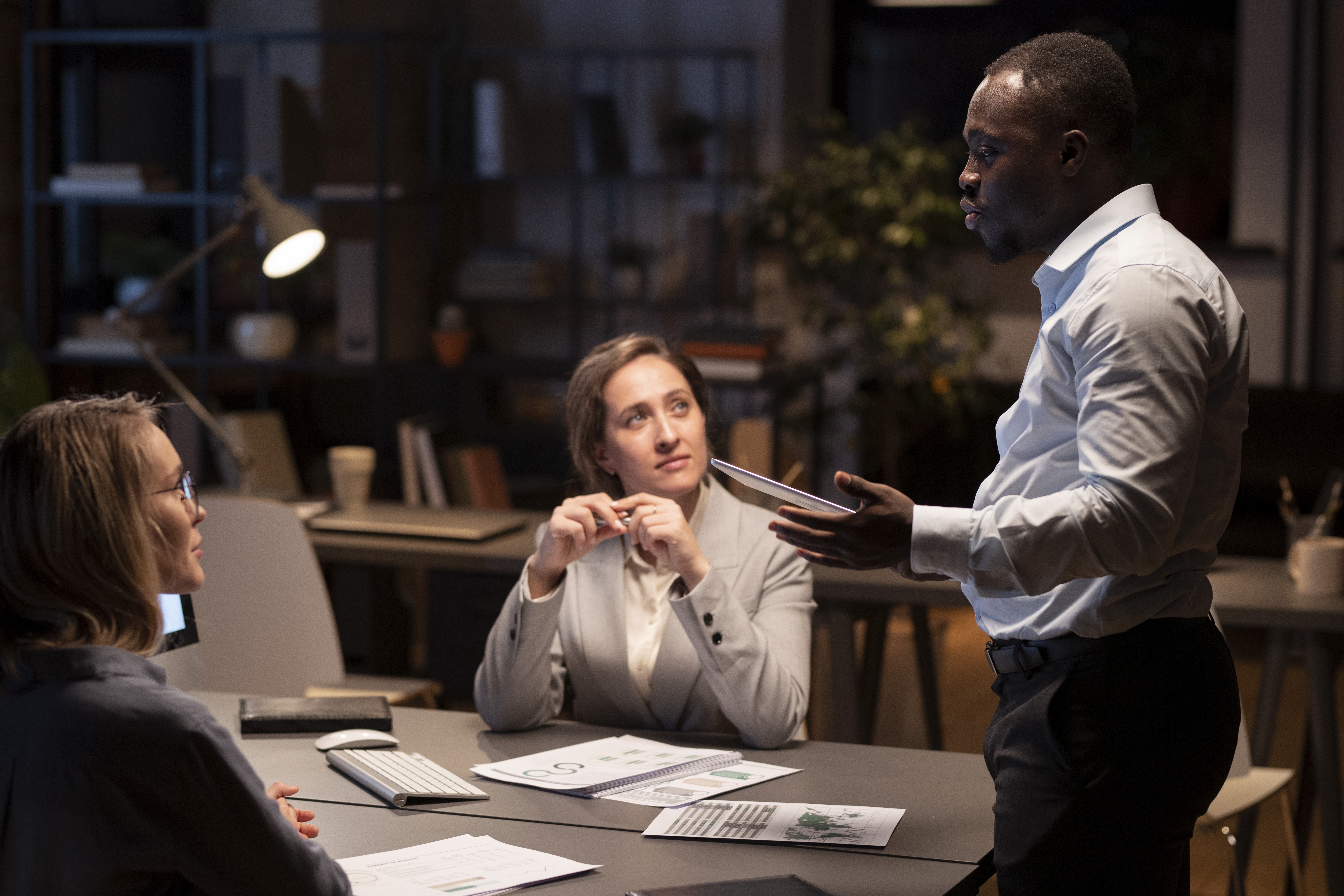 Business professional giving a presentation to colleagues during a meeting in a modern office.