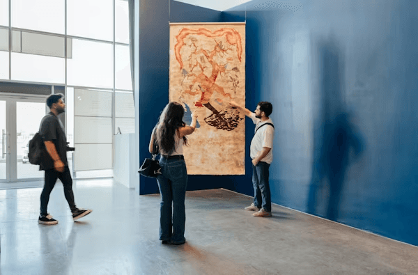 High school student conducting art history research with a PhD mentor, reviewing archival documents and art reproductions