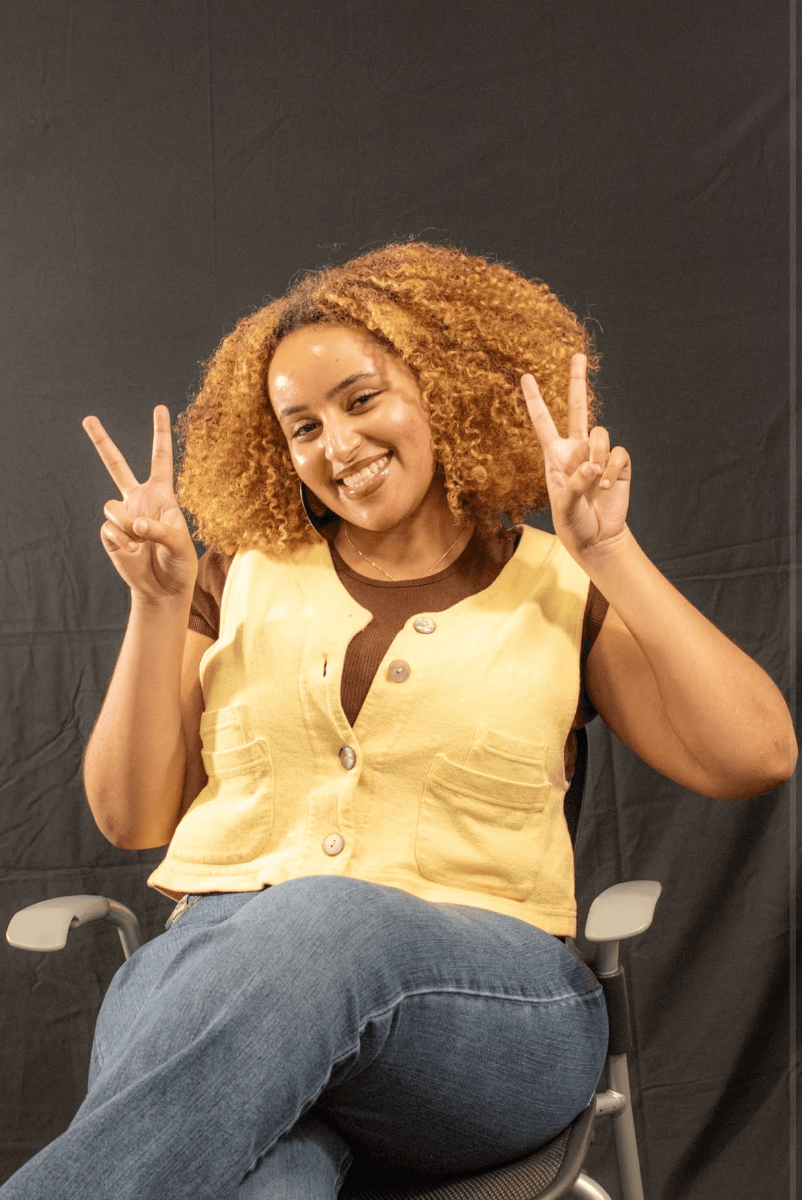 Me, pictured on a chair holding up two peace signs.