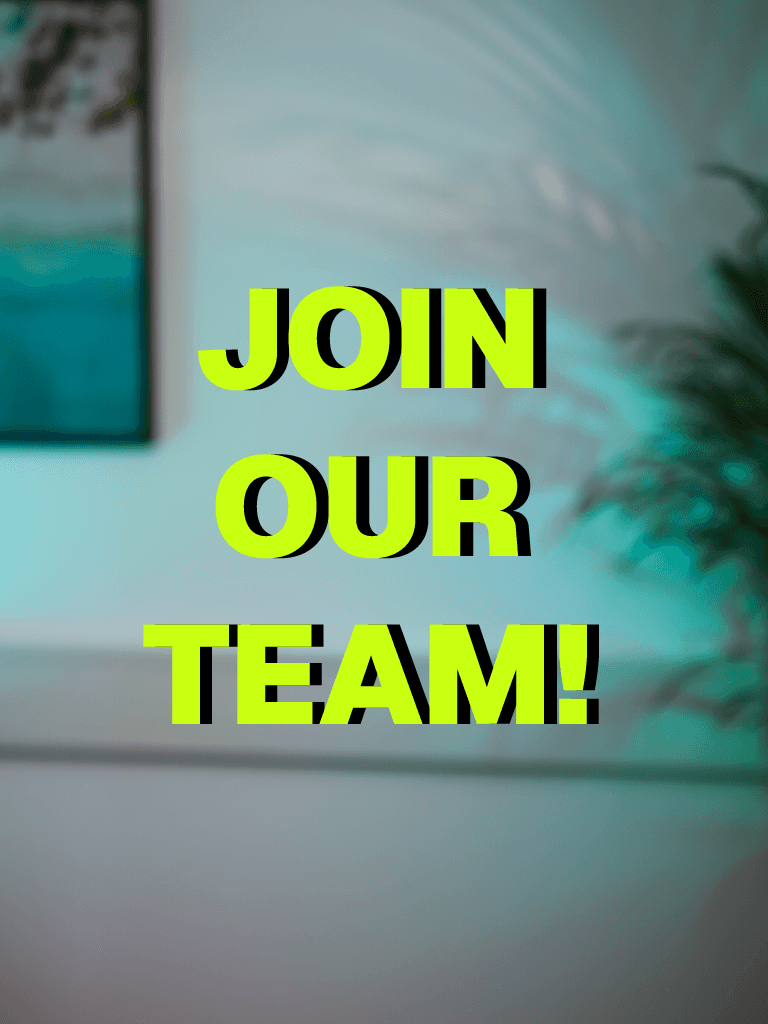 A woman with short curly hair wearing a black t-shirt looks into the camera.