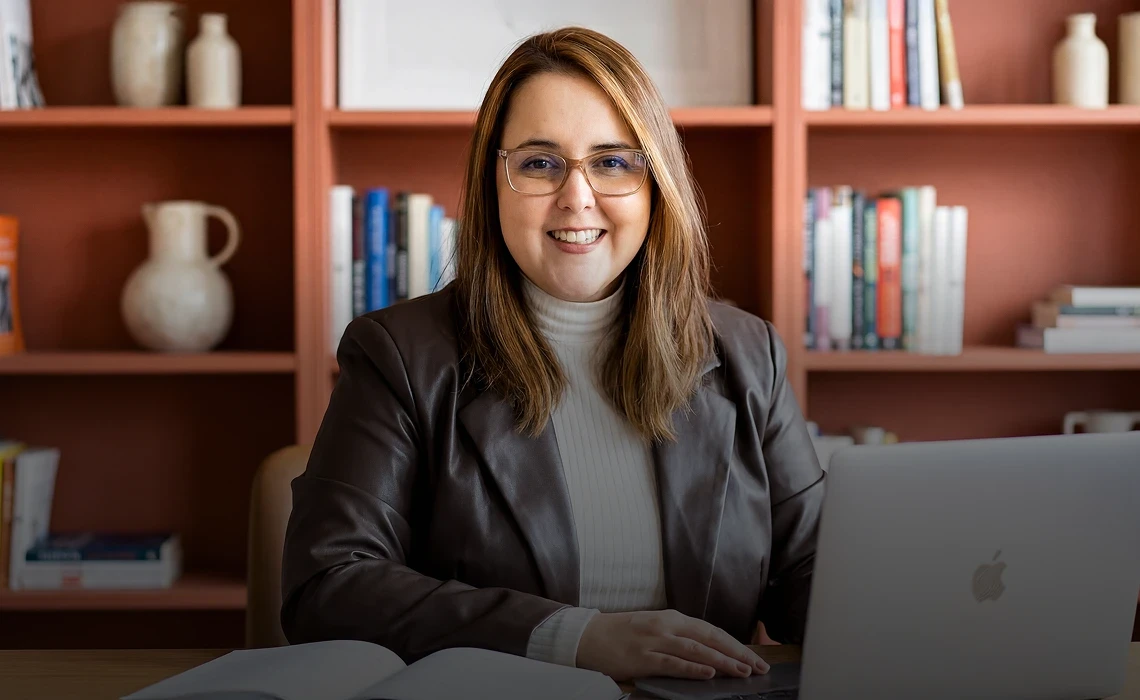 Nathalia Bittencourt, consultora de negócios, sorrindo em sua mesa de trabalho