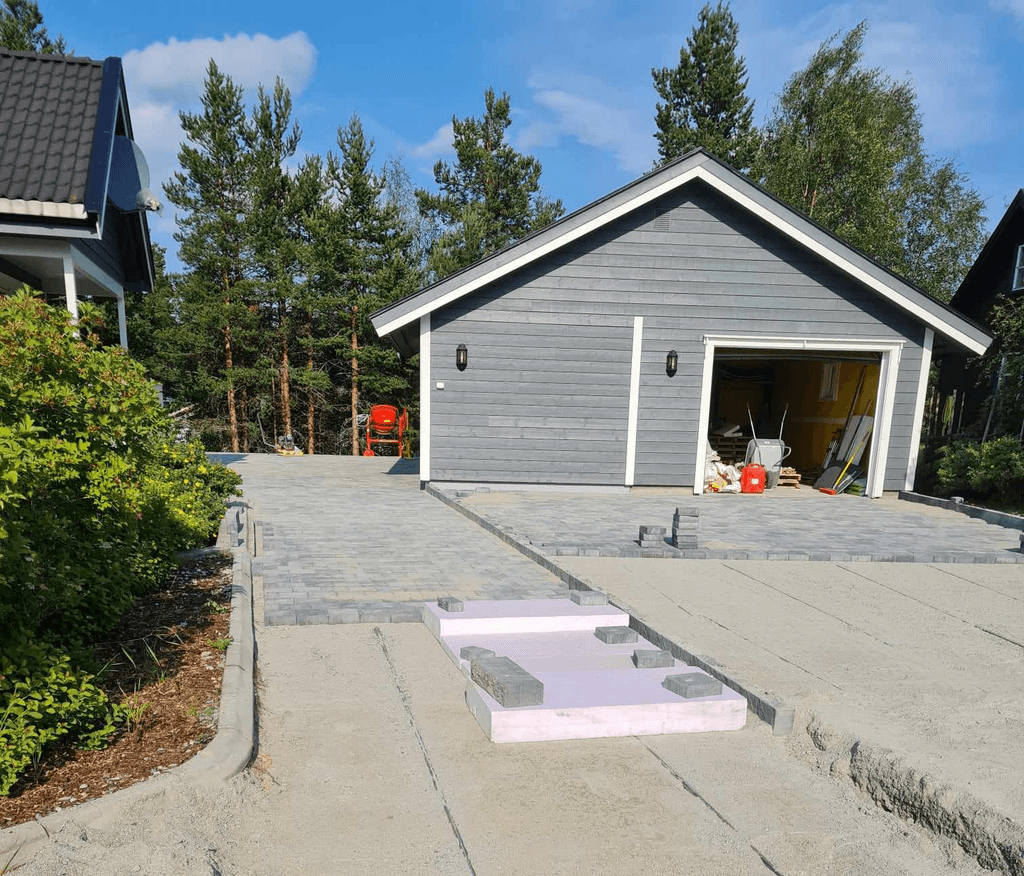 Garasje med steinlagt parkeringsplass.