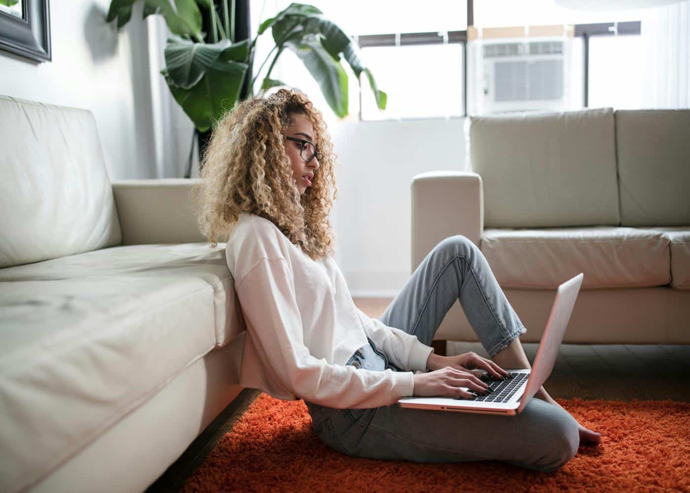 Woman working from home sitting on floor in front of couch