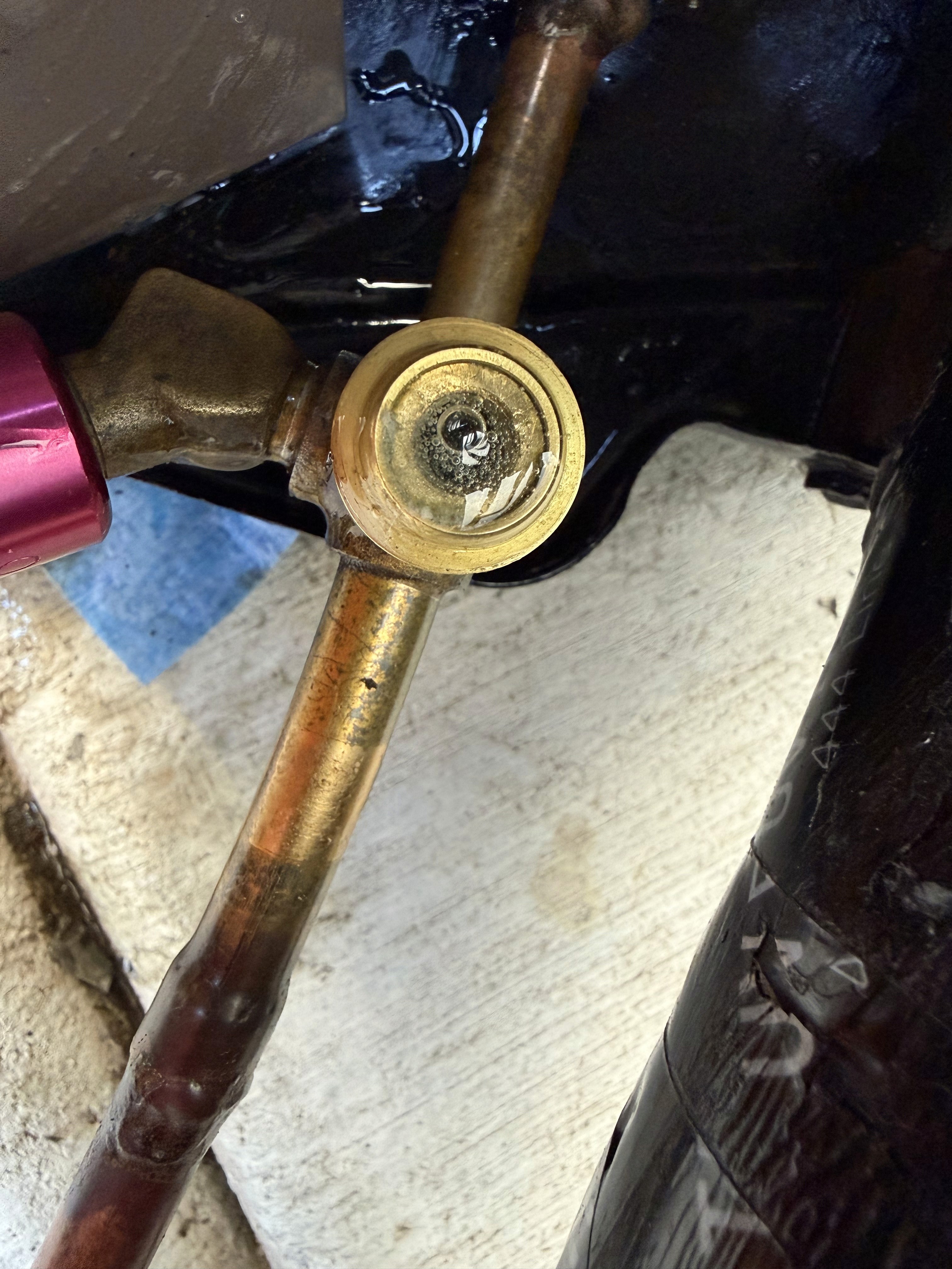 The point of loss: the brass discharge service valve, where the high-pressure line exits the compressor.
