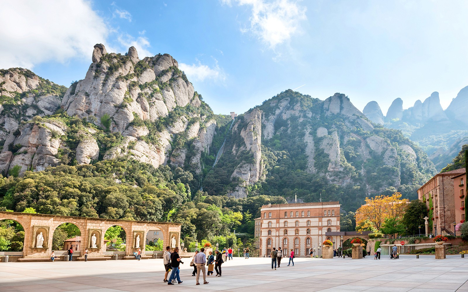 Montserrat-hegy kilátás turistákkal az udvarban, Katalónia, Spanyolország.