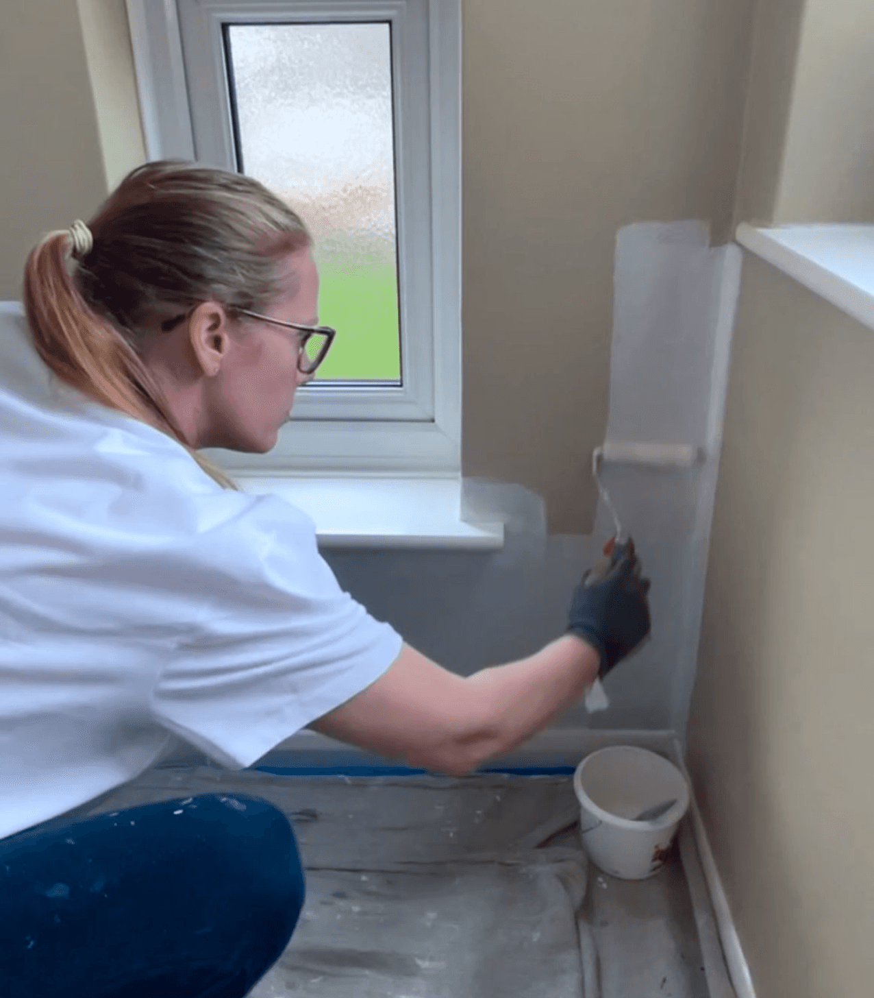 CEO Patricia, painting the corner of a wall with white paint.